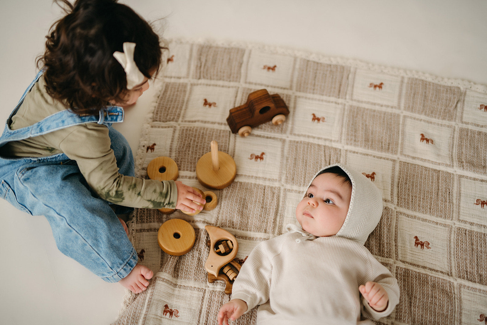 Children Playing with wooden toys on a neutral blanket